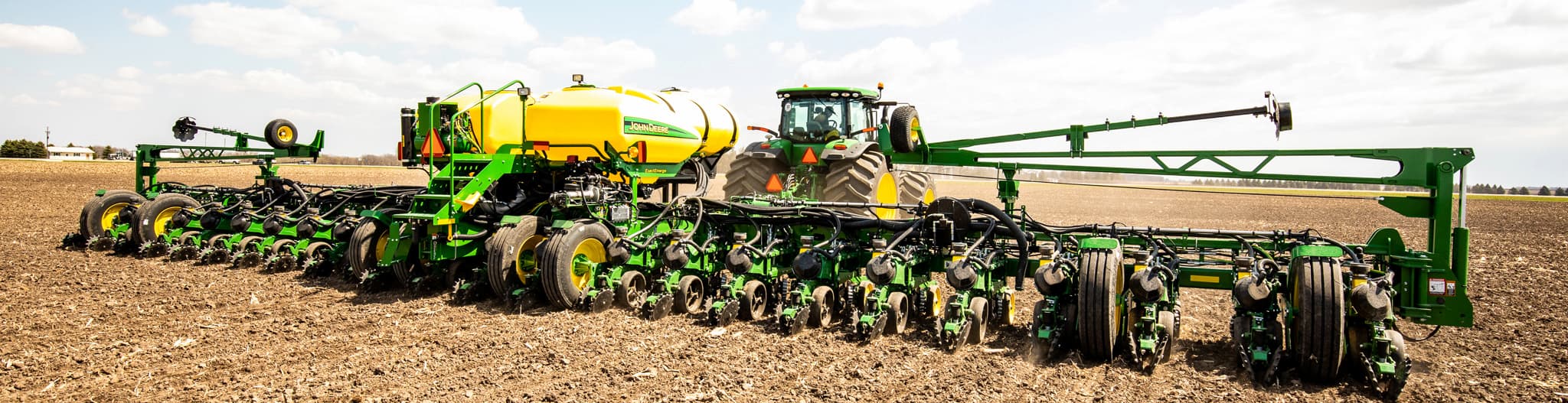 Tractor pulling a seed planter attachment through a dirt field