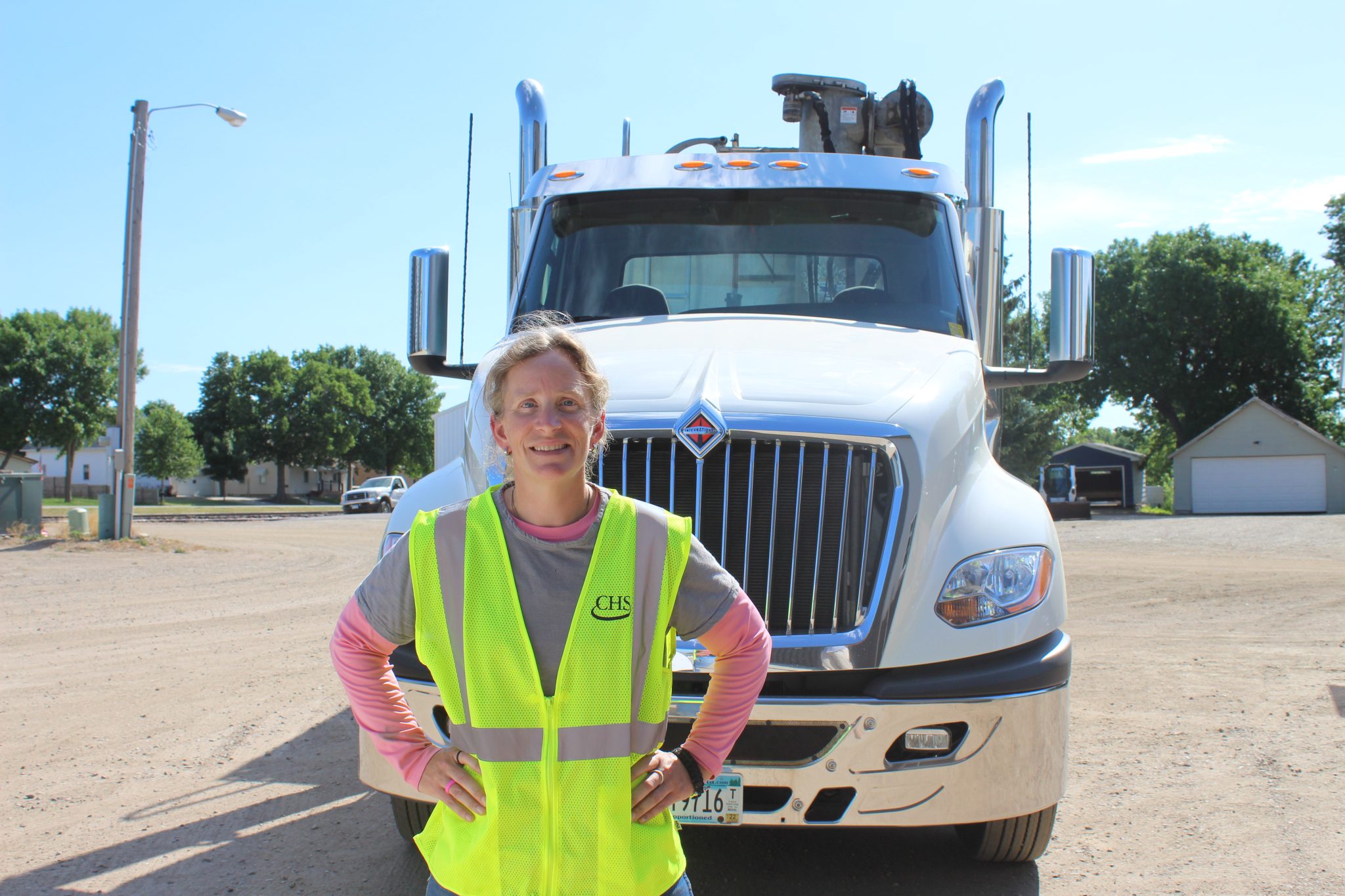 Woman standing in front of semi-truck wearing a yellow CHS safety vest